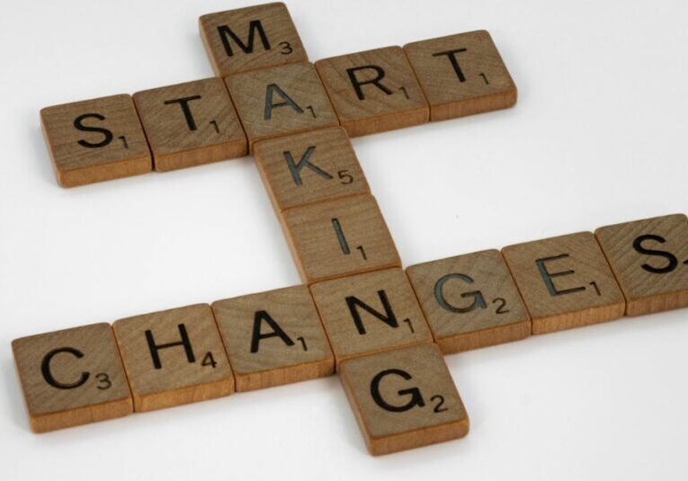 Top view of Scrabble tiles forming the phrase 'Start Making Changes' on a white background.