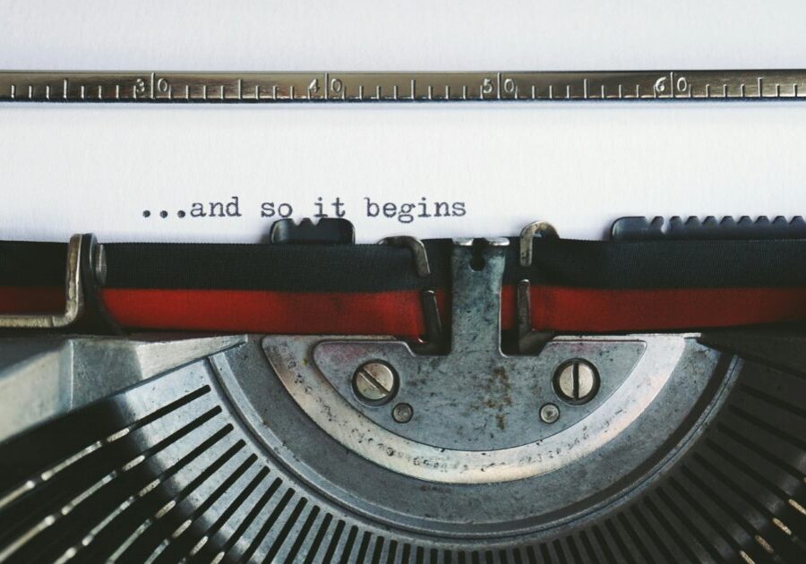 Close-up of a vintage typewriter with the quote '...and so it begins'.